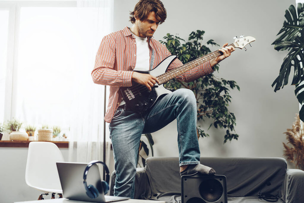 Man playing electric guitar and recording music into laptop - Foto, Imagen