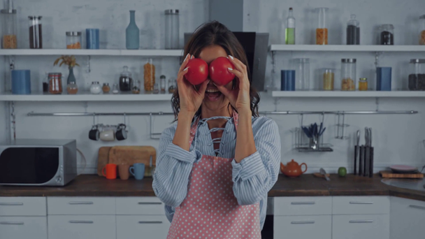 Donna che balla e tiene i pomodori durante la cottura in cucina  - Filmati, video