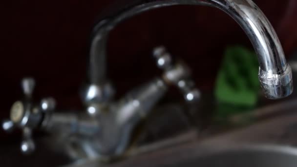 Kuchyňský kohoutek a dřez v kuchyni. Mužská voda otočí knoflíkem a otevře kohoutek - Záběry, video