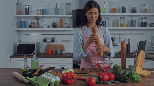 Nainen mauste salaatti lähellä vihanneksia keittiössä  - Materiaali, video