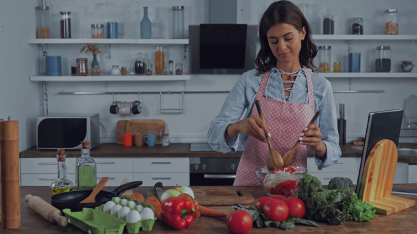 Femme mélangeant salade près de légumes mûrs dans la cuisine  - Séquence, vidéo
