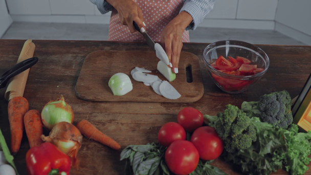 Vágott kilátás nő vágás hagyma közelében érett zöldségek a konyhában  - Felvétel, videó