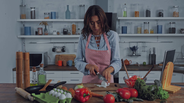 Kobieta płacze podczas krojenia cebuli w kuchni  - Materiał filmowy, wideo