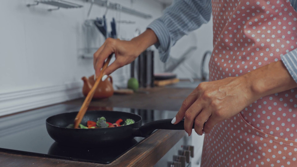 Vista cortada de mulher fritando legumes no fogão   - Filmagem, Vídeo