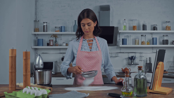 Kobieta sieje mąkę z sita podczas gotowania w kuchni - Materiał filmowy, wideo