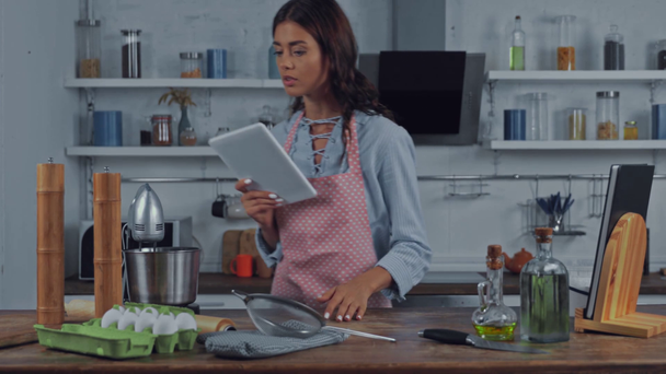 Frau benutzt digitales Tablet in der Nähe von Rohstoffen in Küche  - Filmmaterial, Video