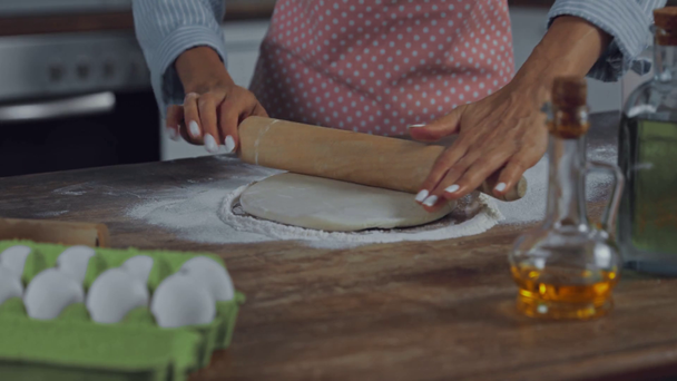 Vista ritagliata di donna rotolamento pasta vicino ingredienti in cucina  - Filmati, video