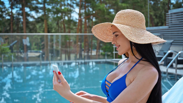 mulher morena em chapéu de palha tomando selfie perto da piscina  - Filmagem, Vídeo