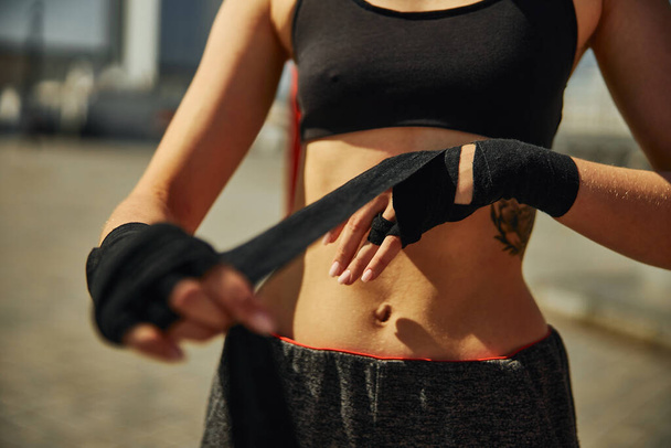 Oříznutý pohled na sportovní břicho sportovní žena, která se chystá na trénink kickbox venkovní - Fotografie, Obrázek