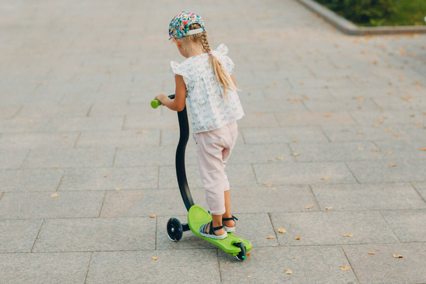 Маленька дівчинка катається на скутері на міській вулиці
. - Фото, зображення