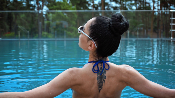 ブルネット女性で水着タッチサングラスでプール - 映像、動画