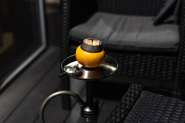 Close up view of a hookah on grapefruit. One bright color on the grey photo.  - Fotó, kép