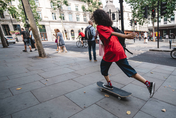Лондон / Великобритания - 08 / 09 / 2020: Молодой человек в красной рубашке катается на коньках в центре Лондона Сохо - Фото, изображение