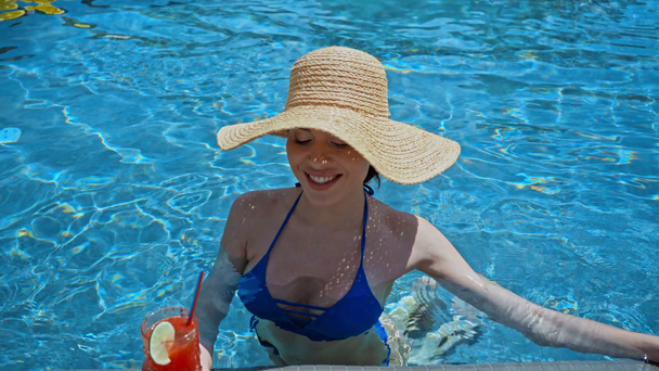 mujer en sombrero de paja beber cóctel en la piscina  - Imágenes, Vídeo