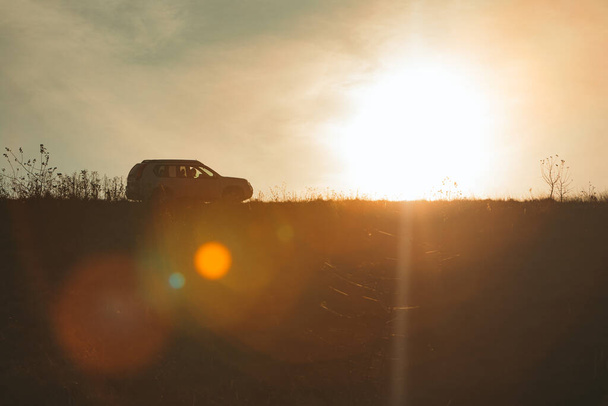 silueta de coche suv en la puesta del sol. espacio de copia - Foto, imagen