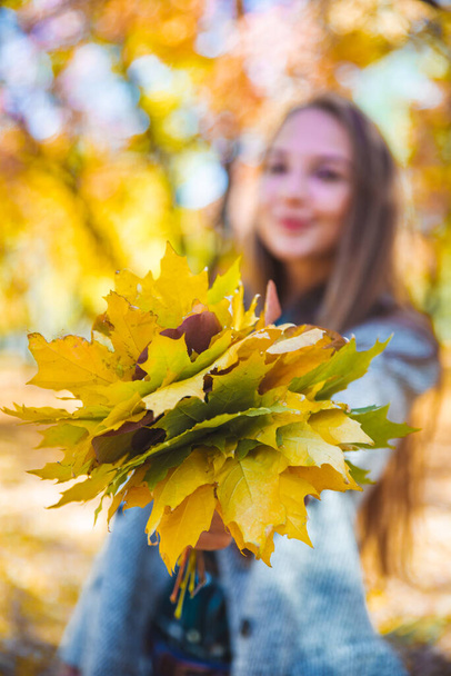 νεαρή όμορφη γυναίκα χαζολογάει με κίτρινο φύλλο σφενδάμου φθινοπωρινή μόδα - Φωτογραφία, εικόνα
