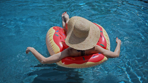 donna nuoto in cappello di paglia nuoto su anello gonfiabile in piscina - Filmati, video