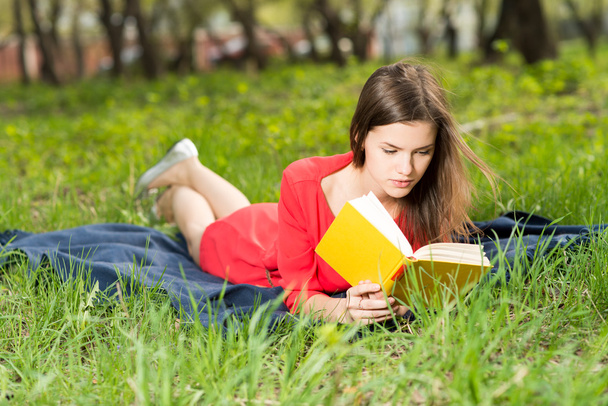 beautiful young girl reads book in park - Фото, изображение