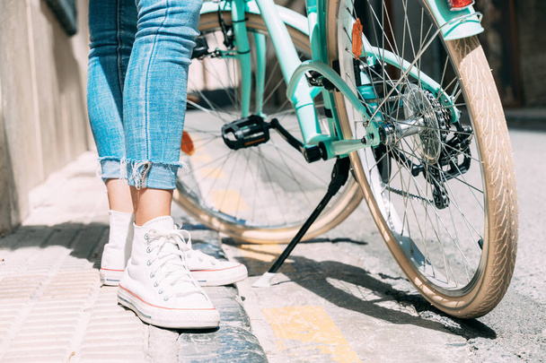 Imagen de cerca de las piernas de una mujer y una bicicleta en una calle vieja. - Foto, imagen
