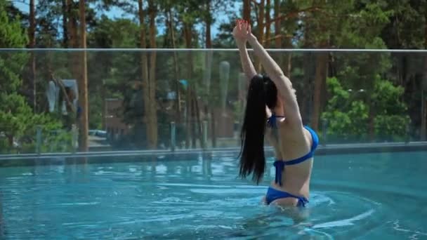 sexy kobieta w strój kąpielowy chodzenie w niebieskiej wodzie w basen - Materiał filmowy, wideo