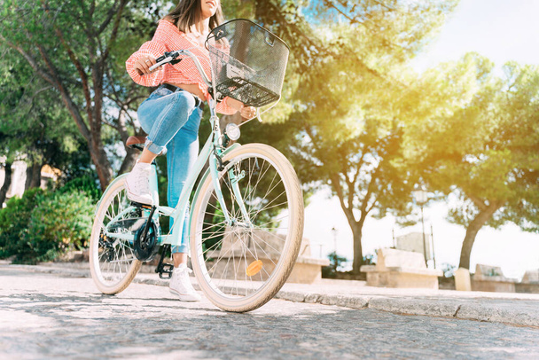 Jonge glimlachende vrouw fietst door de straten van een oude stad. - Foto, afbeelding