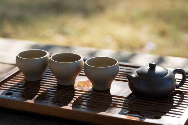 Китайская чайная церемония. Керамический чайник из глины и миски на деревянном фоне. - Фото, изображение