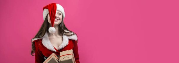 Красивая молодая женщина в костюме Санта Клауса на красном фоне. - Фото, изображение