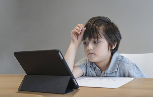 Kid self isolation using tablet for his homework,Child doing using digital tablet searching information on internet during covid 19 lock down,Home schooling,Social Distance,E-learning online education - Photo, Image