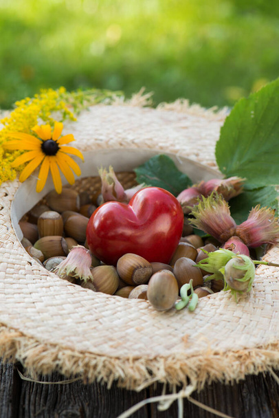 красное сердце с орехами сена в соломенной шляпе - Фото, изображение
