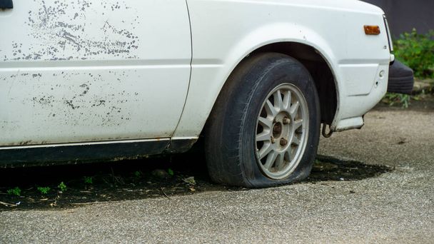 Viejo coche abandonado desgastado y oxidado con neumático plano - Foto, Imagen