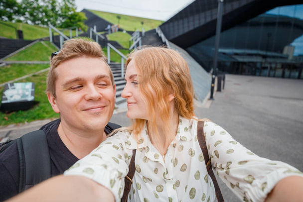 Chwytając jasne chwile. Radosna młoda, kochająca się para robiąca selfie. Ładni turyści zrobić śmieszne zdjęcia do bloga podróży - Zdjęcie, obraz