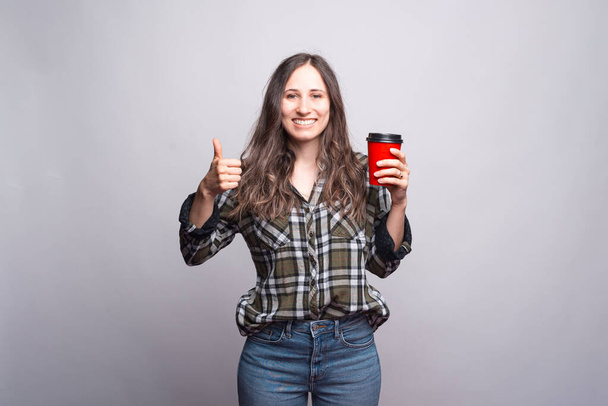 Vidd el a kávét. Boldog fiatal nő mutatja hüvelykujját fel és tartsa - Fotó, kép