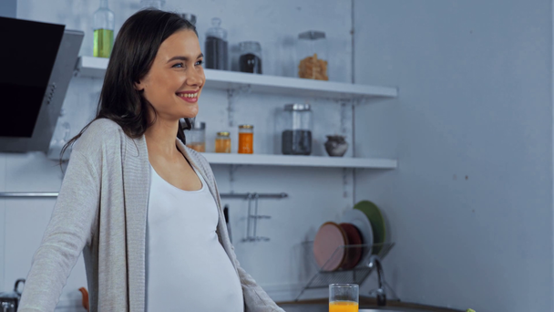 Zwangere vrouw drinkt sinaasappelsap in de keuken  - Video