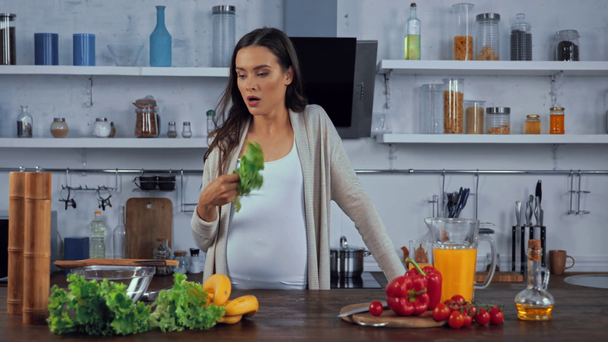 Kobieta w ciąży uczucie gorąca i picia soku pomarańczowego w kuchni  - Materiał filmowy, wideo