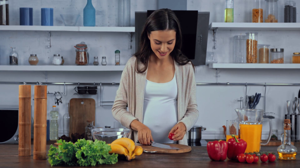 Mujer embarazada cocinando ensalada en la cocina  - Imágenes, Vídeo