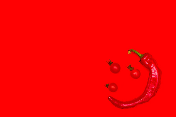 czerwony gorąca papryka z pomidorami wiśniowymi na czerwonym tle widok z góry jeden - Zdjęcie, obraz