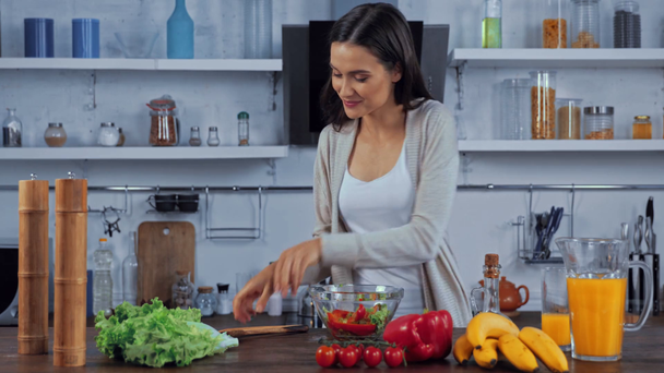 Junge Frau gibt Öl in Salat auf Küchentisch - Filmmaterial, Video