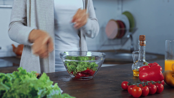 Καλλιεργημένη θέα της γυναίκας ρίχνει λάδι στη φρέσκια σαλάτα στην κουζίνα  - Πλάνα, βίντεο