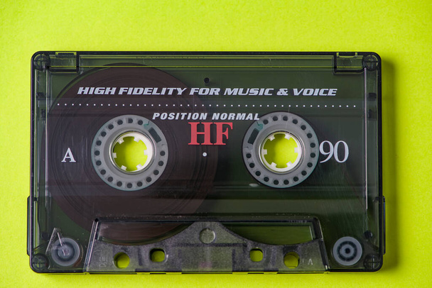 Вид зверху аудіокасети з заплутаною стрічкою на яскраво-жовтому тлі з копіювальним простором, мінімалістична композиція
 - Фото, зображення