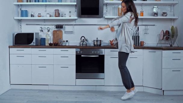 Ciężarna kobieta tańczy i skacze w kuchni  - Materiał filmowy, wideo