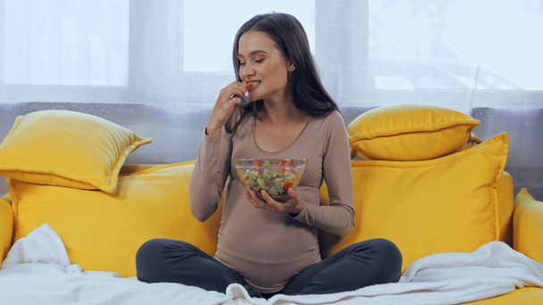 Mujer embarazada comiendo ensalada en el salón - Metraje, vídeo