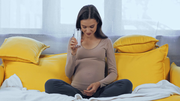 Mujer embarazada bebiendo leche en el sofá  - Imágenes, Vídeo