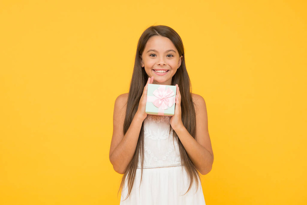 Online shop. boxing day concept. small child on yellow background. holiday shopping sales. beauty box. surprise for birthday. long awaited present. happy childhood. cheerful little girl hold gift box - Photo, image