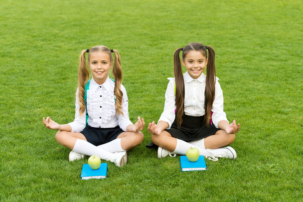 Perfect school children sit on grass with books, practice meditation concept - Foto, afbeelding