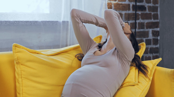 Mujer embarazada que sufre de calor en el sofá  - Metraje, vídeo