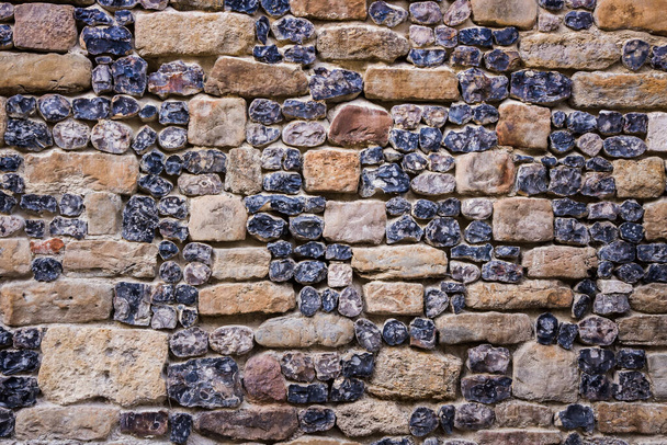 Древняя стена из черных и бежевых камней - Фото, изображение