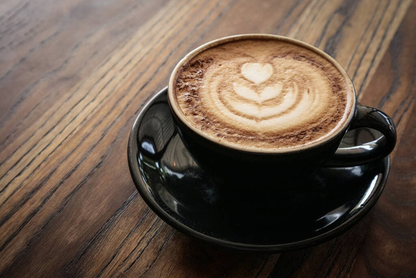 A cup of coffee with latte art on top on wooden table, top view - Foto, Imagem