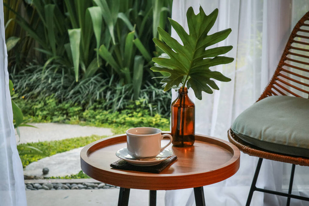 Küçük masası, sandalyesi ve kahvesi olan güzel bir tropikal teras veya balkon. - Fotoğraf, Görsel