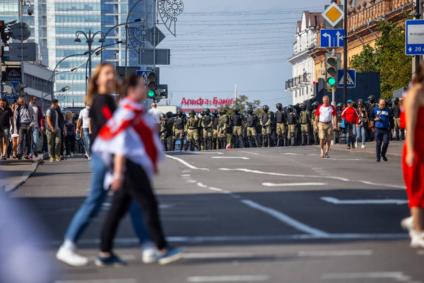Minsk, Belarus- August 30, 2020 Peaceful protest of people moves along Nezavisimosti prospekt. Police fighters on the background. - Фото, зображення