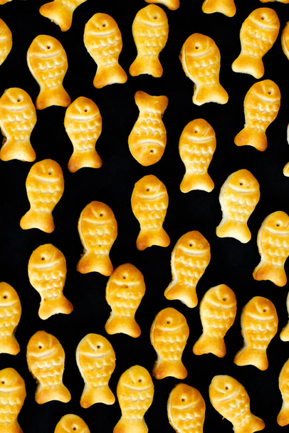 Mini fish shaped crackers on black surface,backgrounds,top view - Photo, Image